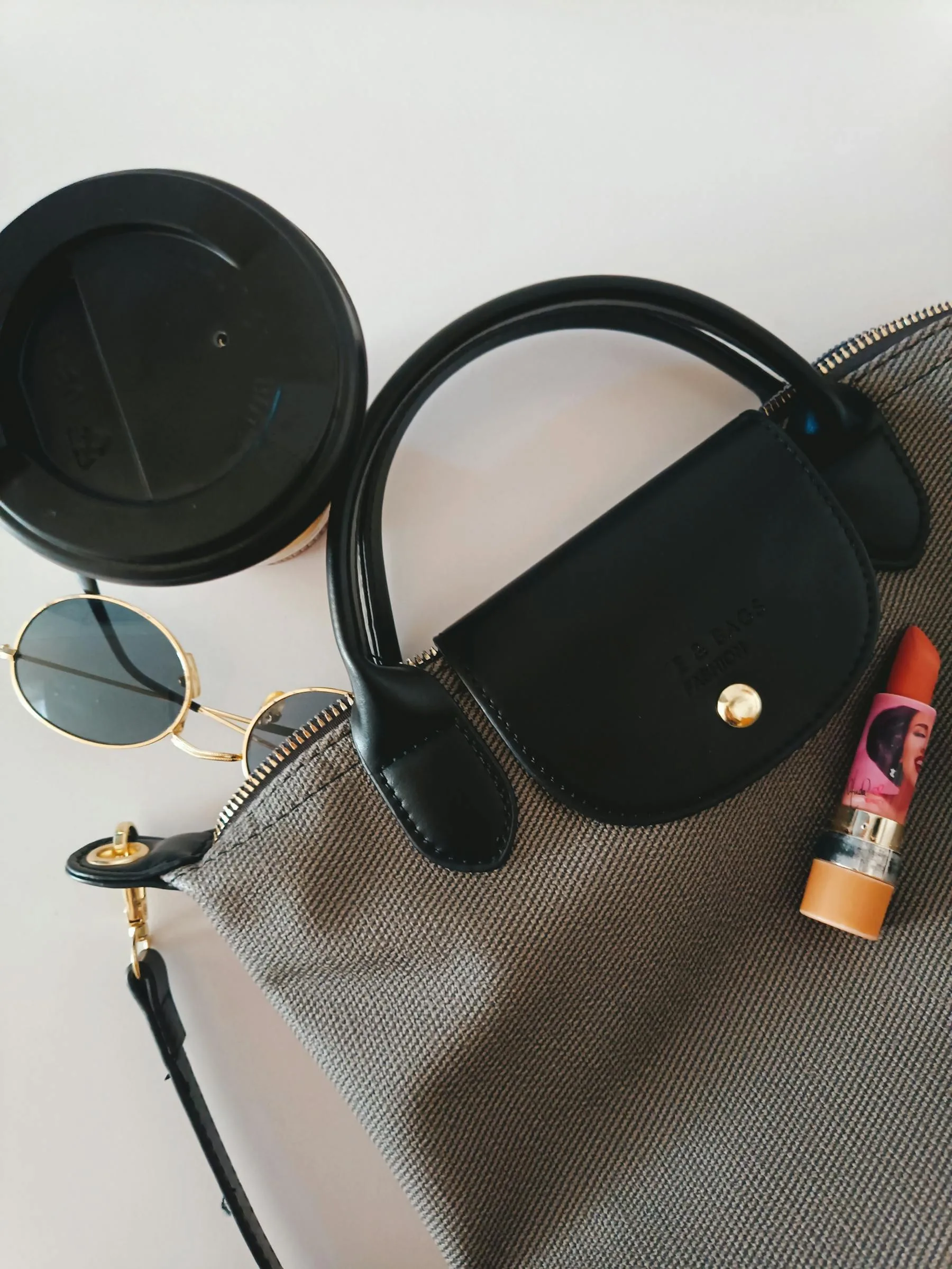 A handbag with sunglasses and fashion accessories arranged in a flat lay