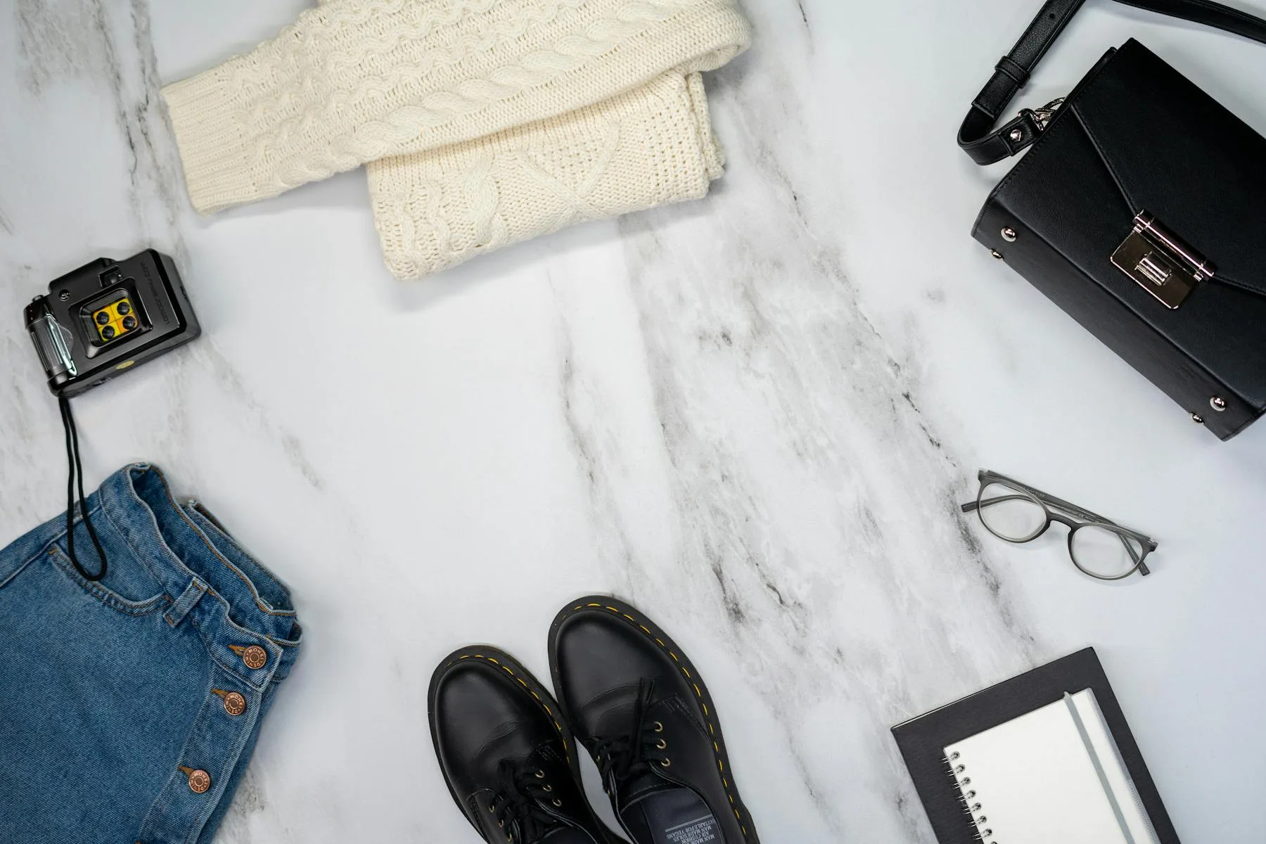 Denim, shoes, and accessories arranged on a marble surface